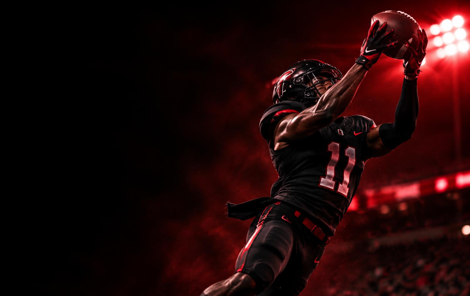 Receiver catching a football under stadium lights